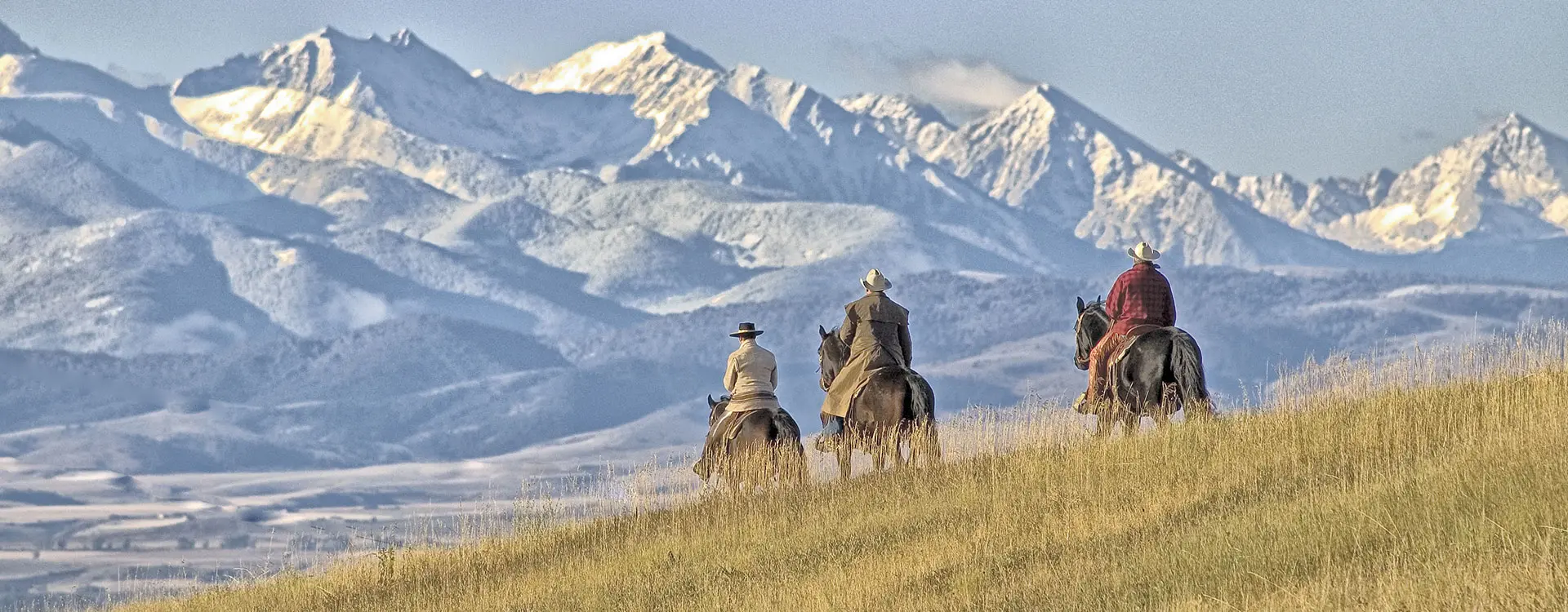 three people of horse in wide open range