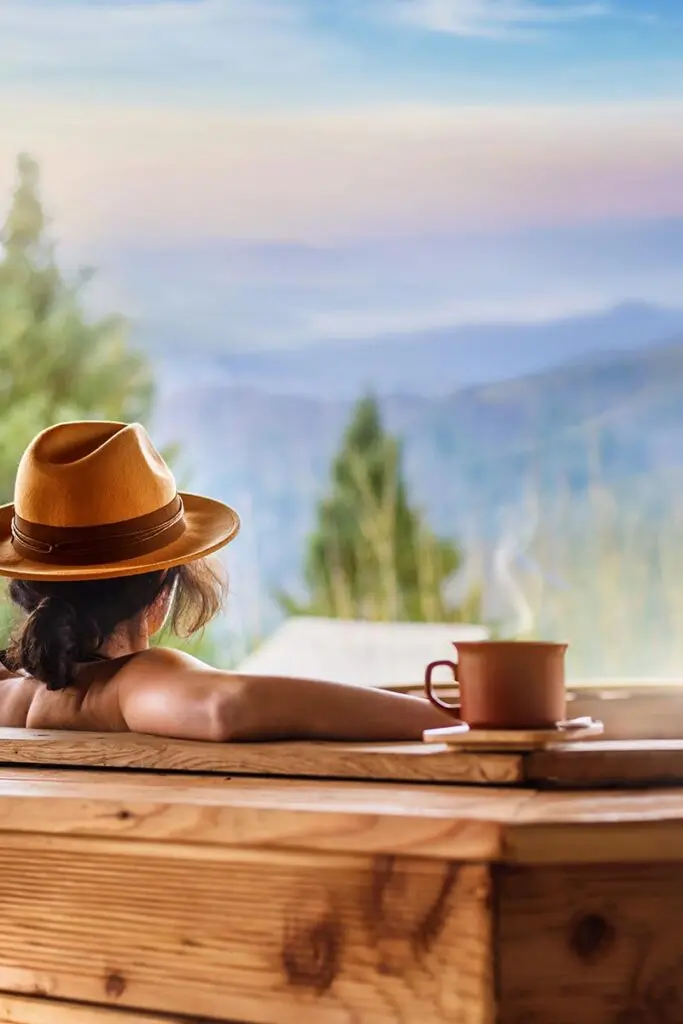 Person in outdoor hot tub overlooking forest